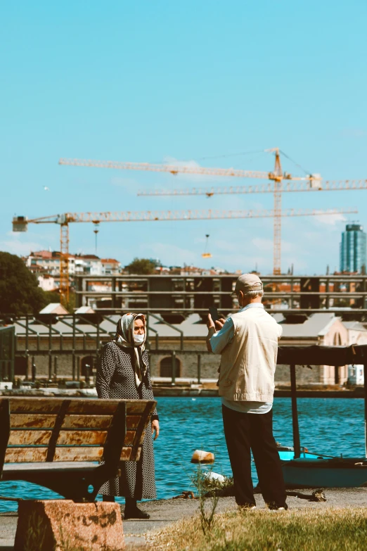 two people are standing by the water taking pictures of themselves