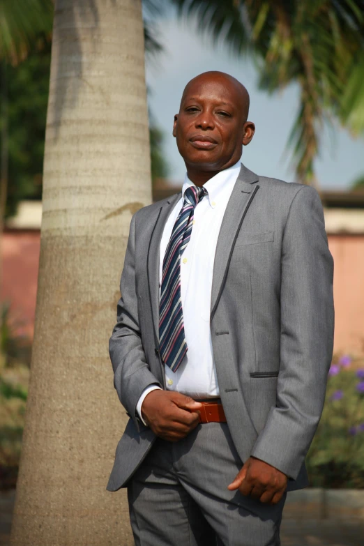 a black man in a business suit standing next to a tree