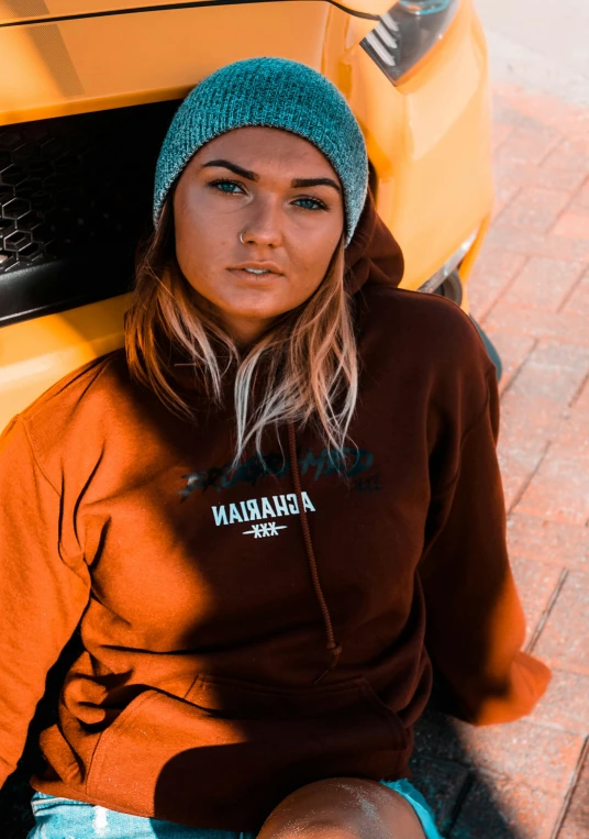 a person sitting on the ground in front of a yellow car