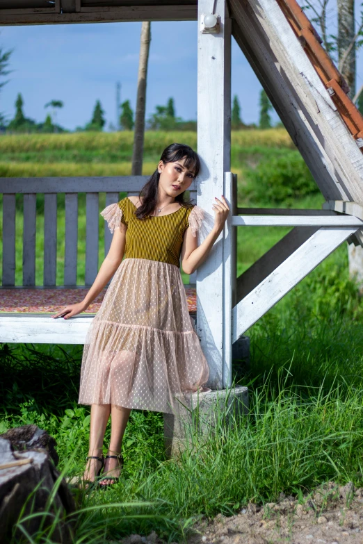 a girl leaning against a white bench next to green grass