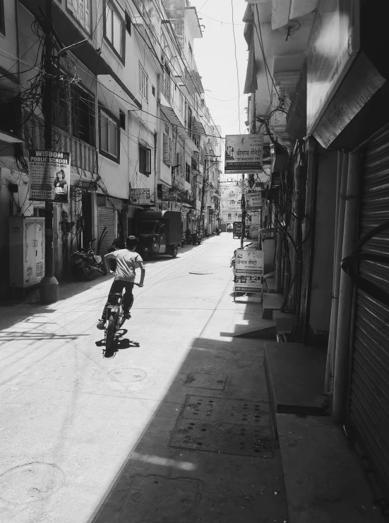 a black and white po of a person riding a bicycle down the middle of a narrow city street