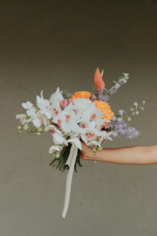 a person holding a bouquet of flowers with white and orange flowers