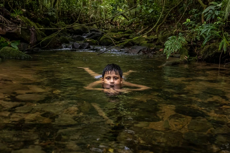 a person swimming in a river surrounded by greenery