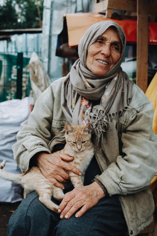 an older woman sitting on a chair holding a cat