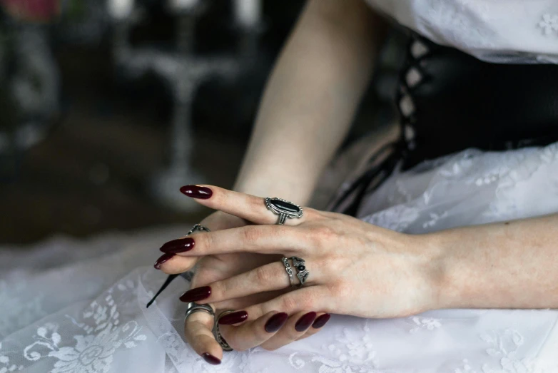 female hands in rings and nails near a white dress