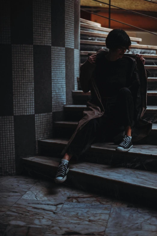 a person sits on the stairs of a staircase