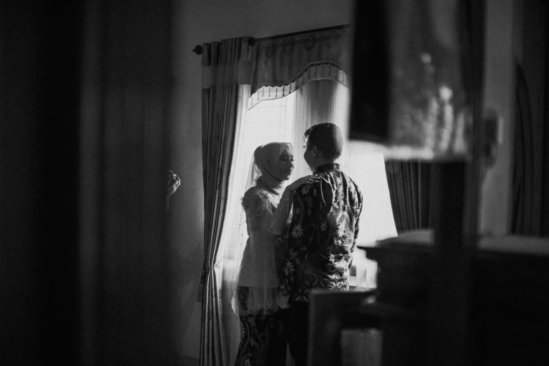 black and white pograph of a man and a woman in front of curtains