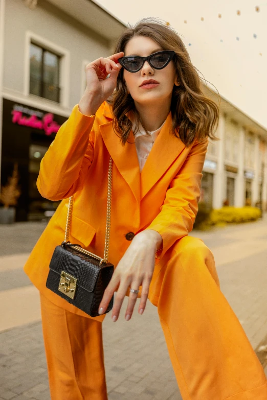 the woman in an orange outfit sits on a sidewalk