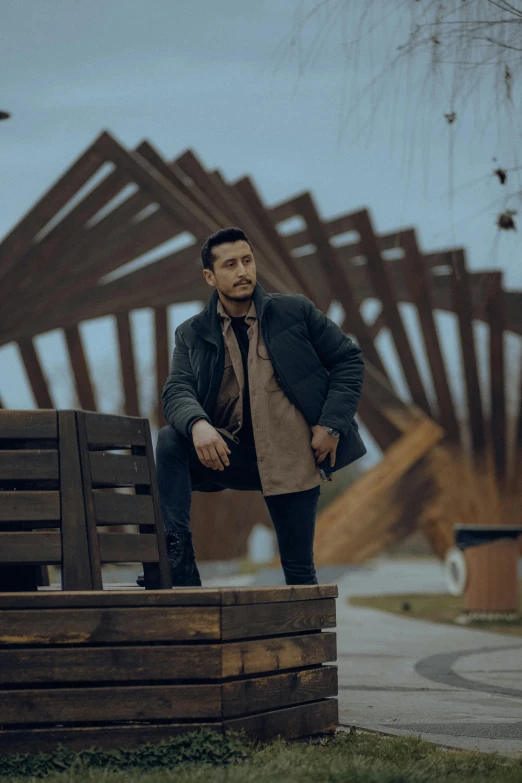 a man leaning against a wooden bench outdoors