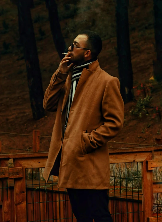 the man is smoking a cigarette in front of trees