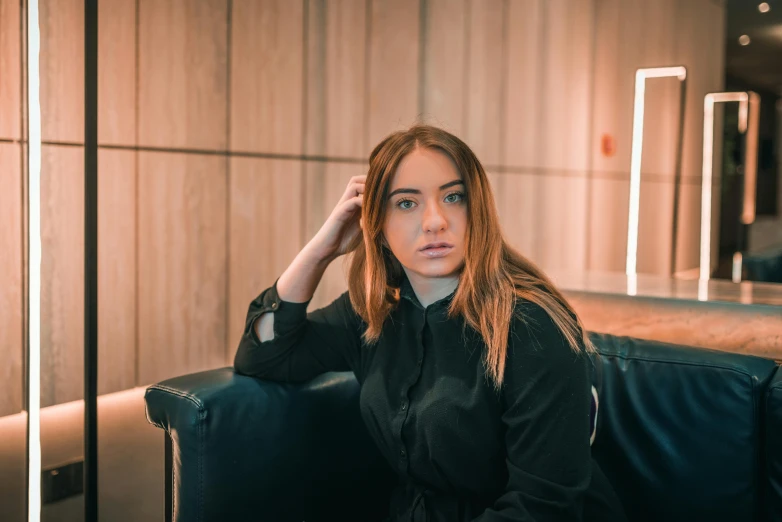 a beautiful young woman sitting on top of a black couch