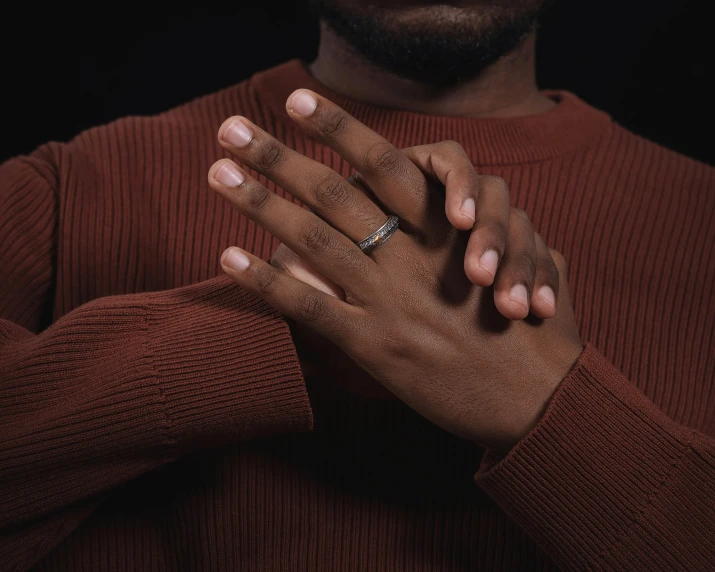 a man in a brown shirt holds his hands together to their chest