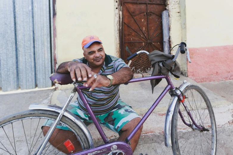 man on bicycle sitting on the pavement next to building