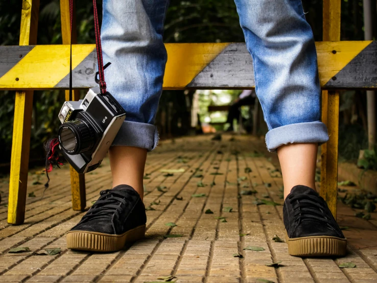 the legs of someone wearing old fashioned sneakers are hanging off of a yellow and wooden platform