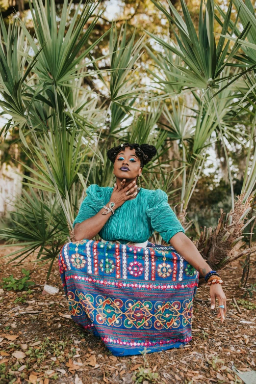 an african woman sitting in front of some palm trees