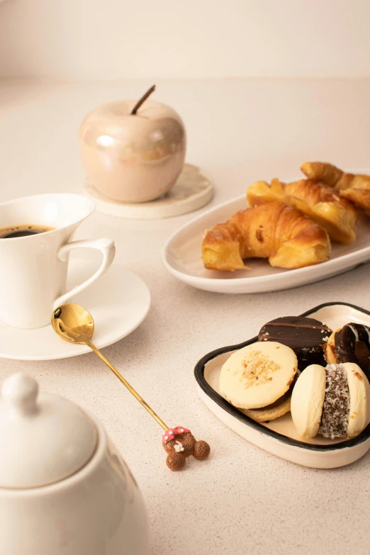 a tray filled with pastries and fruit next to a white cup of coffee