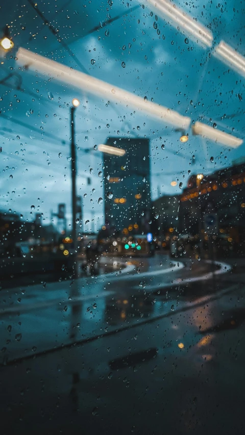 rain is seen in the car window as it travels down a road