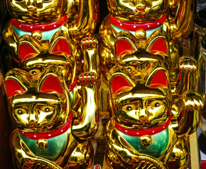 many gold and red metal cat statues sitting side by side