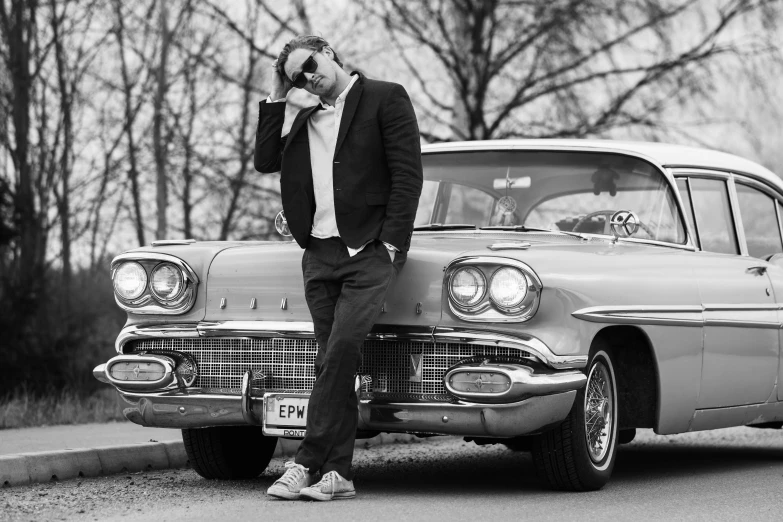 black and white pograph of a man standing next to a car