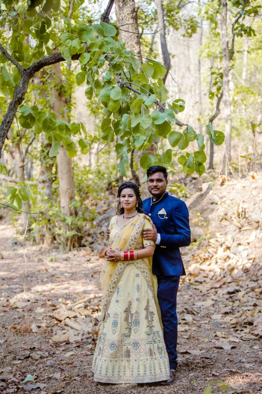 a bride and groom pose for a portrait together in the woods