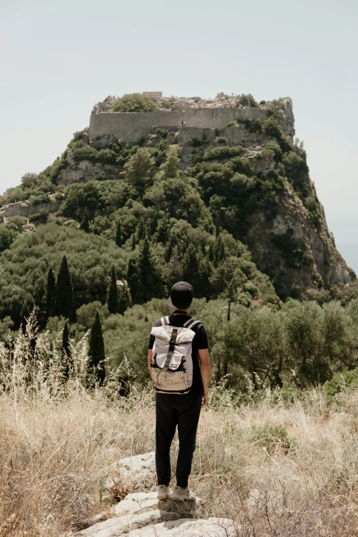 a person stands on a rock looking out at a hill