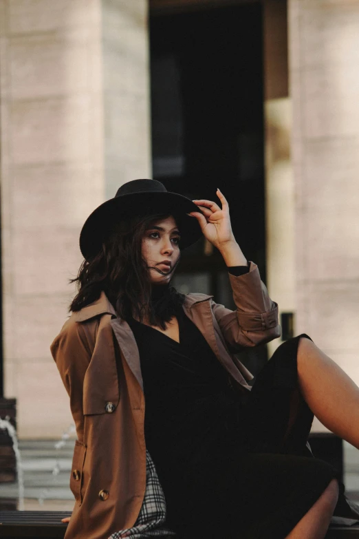 a woman with a hat is sitting on a ledge