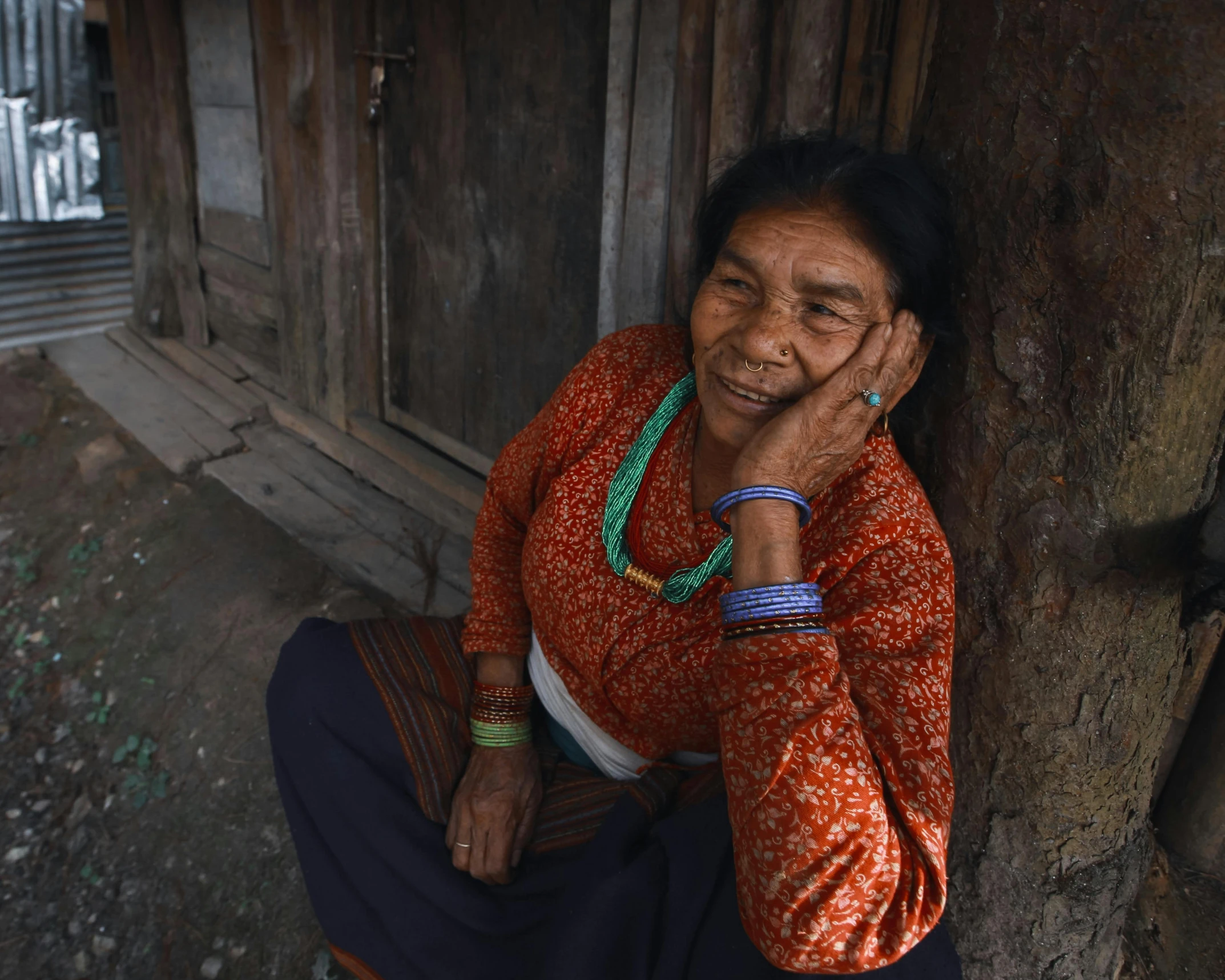 an old woman is sitting against the side of a tree