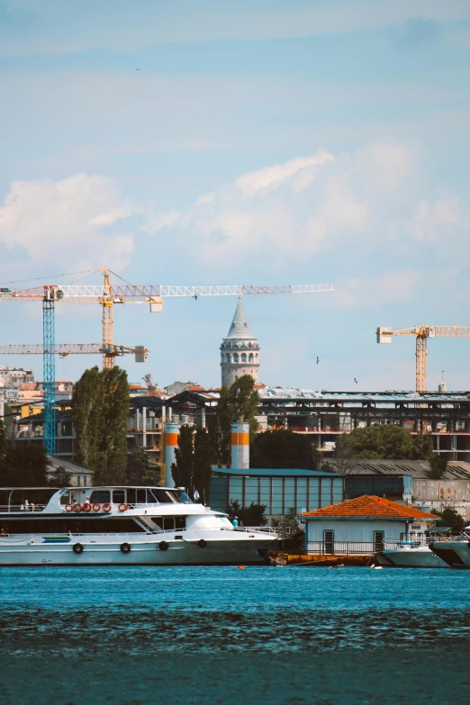 many cranes in the background behind a white boat