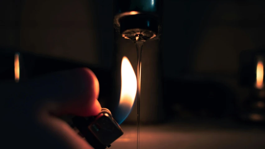 a person holding an lighter in front of a bottle