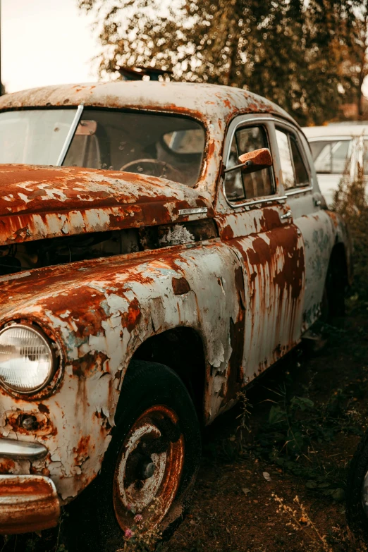 an old rusted car sits in a junk yard