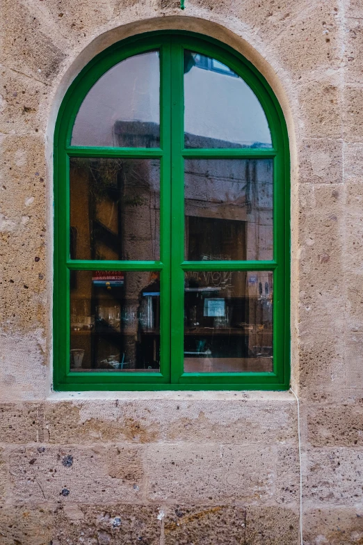 a stone building with green windows and a street lamp in front