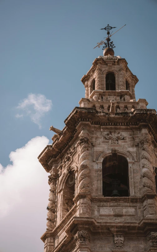 the clock tower on top of the building has a weather vane in the center