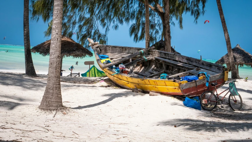 a yellow boat rests on the beach surrounded by trees