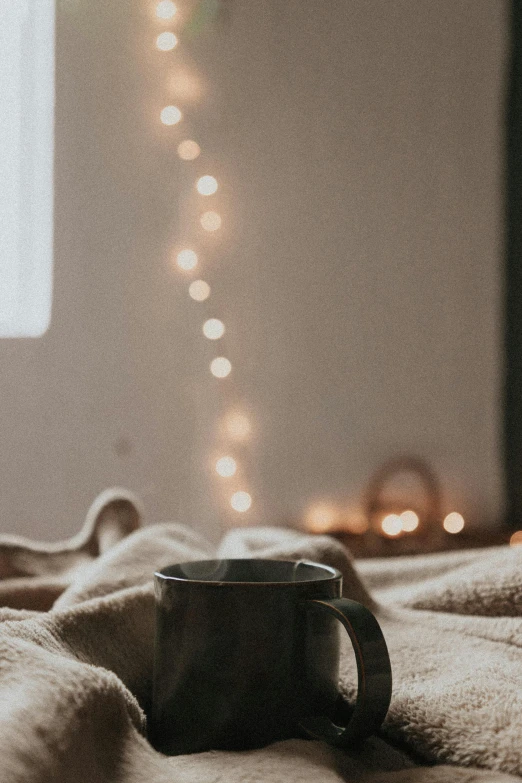 a cup sitting on a blanket in the middle of a bed