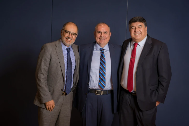 two men and a man in a suit pose for a picture