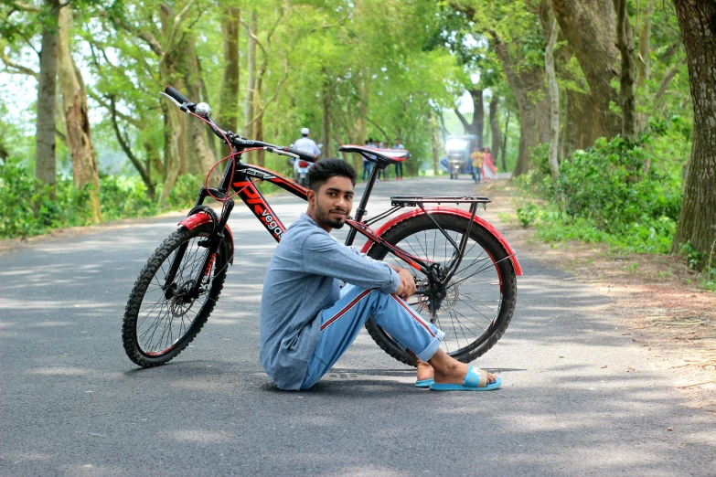 a man sitting on the side of a road near a bike