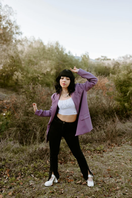 a woman standing outside in a field with her hands in the air