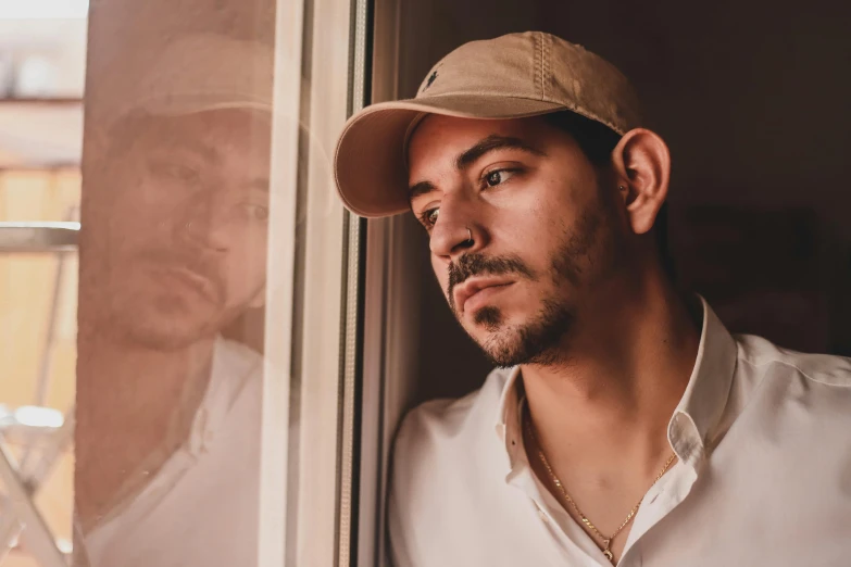 a man wearing a hat and looking out of a window