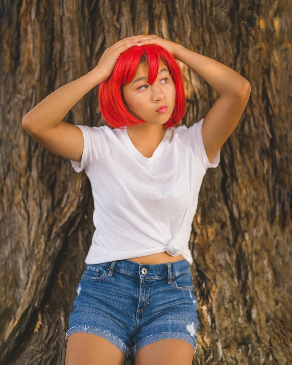 a woman with red hair is posed in front of a tree