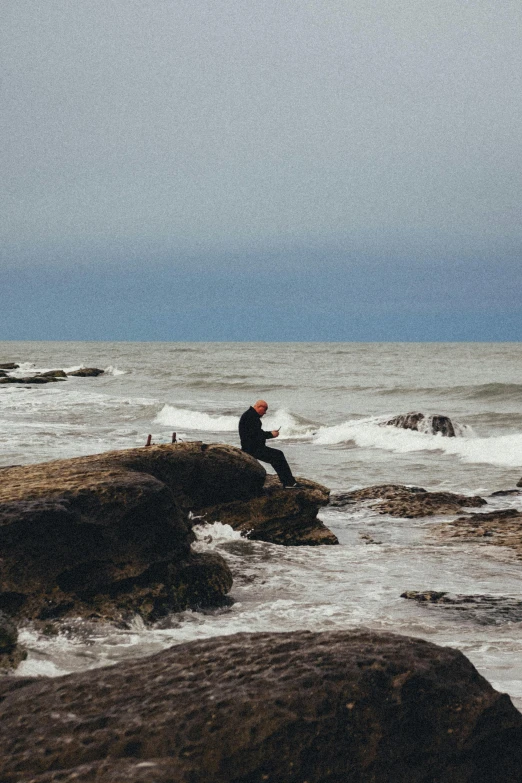 a man standing on rocks near the ocean with an ocean view