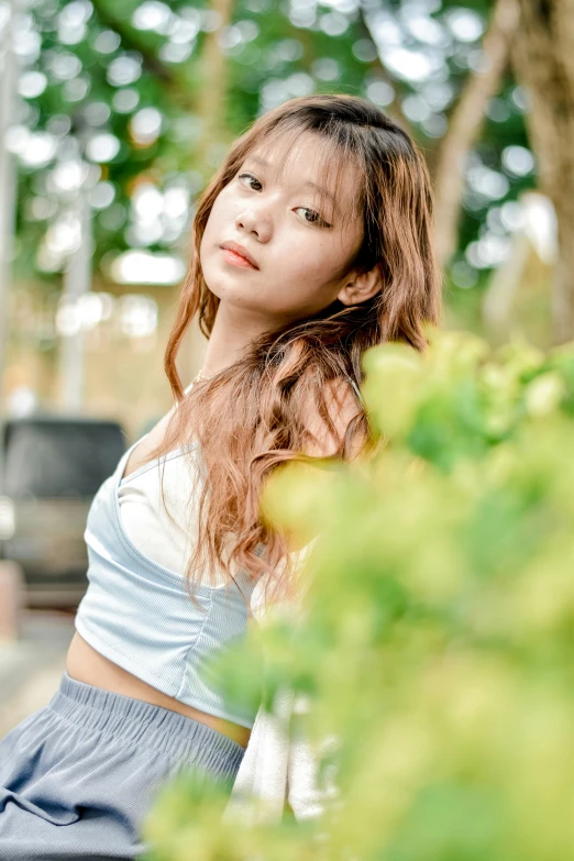 a woman sitting on top of a wooden bench next to a tree