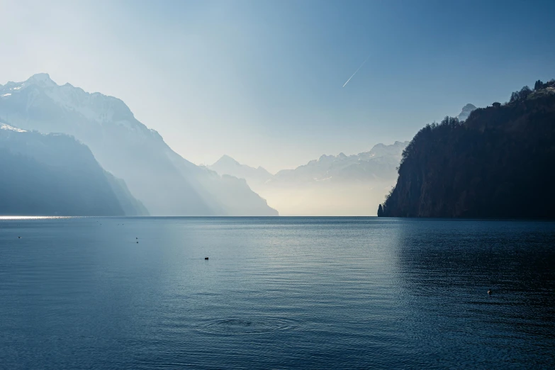 several boats sitting in the blue waters near mountains