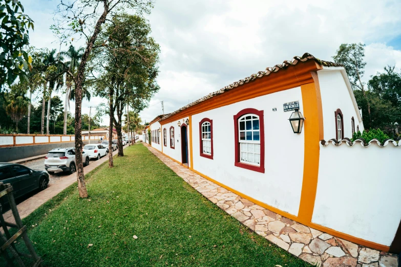 a house with a white and orange wall is next to a grassy area