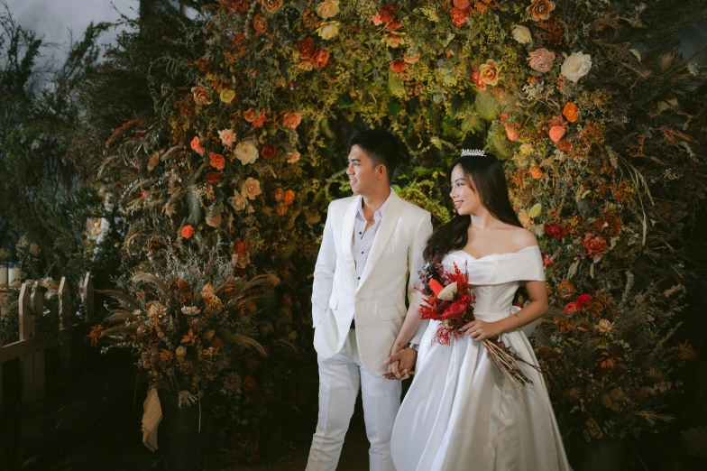 the bride and groom are standing by an arrangement of flowers