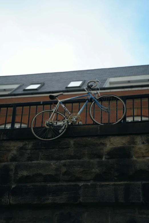 the bicycle is hanging on the fence near the building