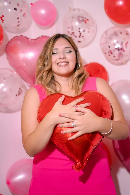 a woman in a pink dress holding a red heart pillow