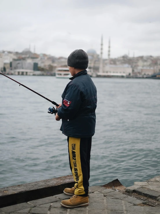 a man holding a fishing rod while looking out to sea