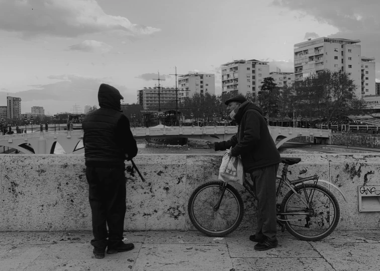 a person standing next to a bike next to another person