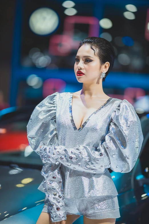 a woman with red makeup and short black hair standing by a car