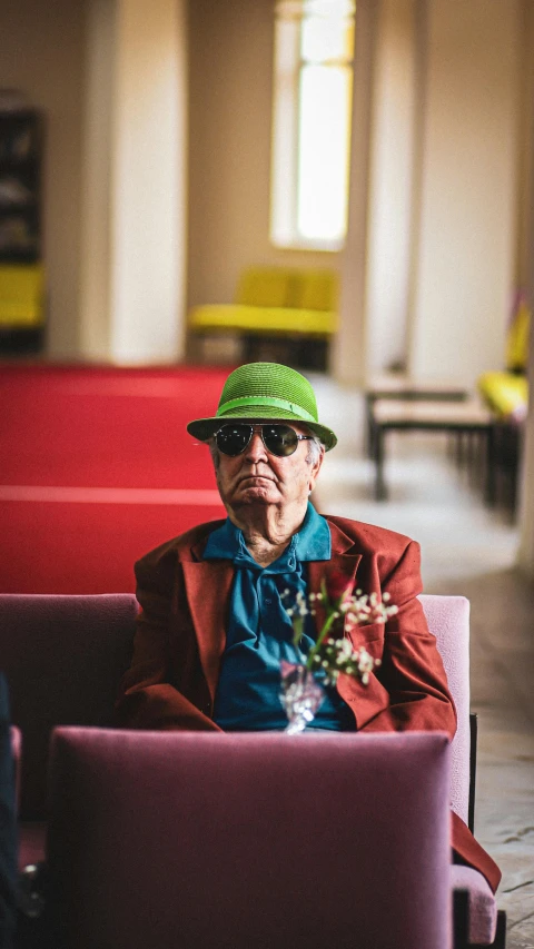 man with flower in his left hand sitting in a red chair